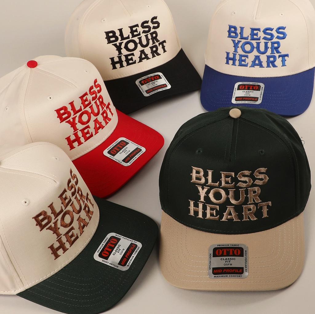 Collection of 'Bless Your Heart' hats in various colors on a light background
