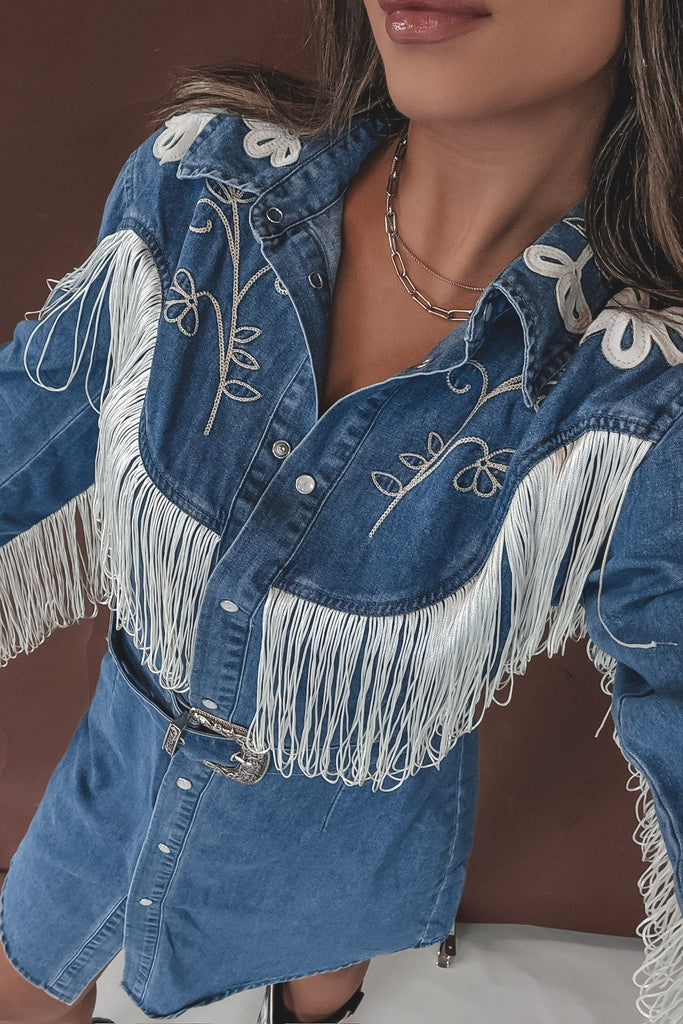 Denim jacket with white fringe and embroidery on a blurred background