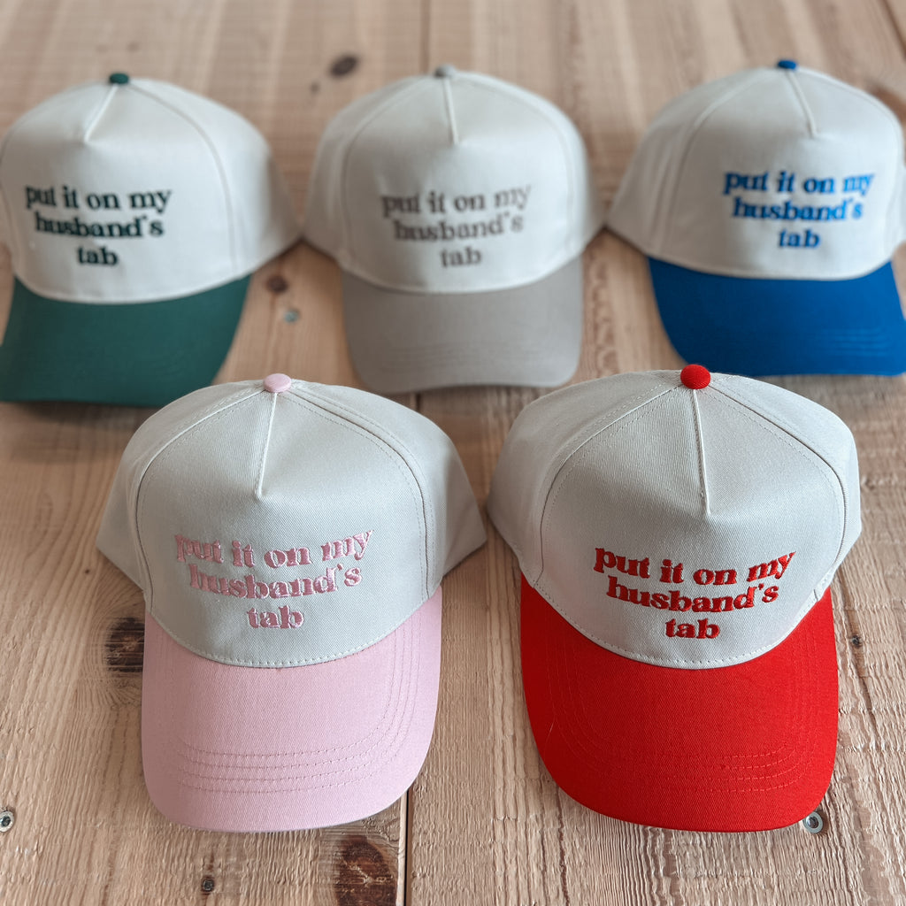 Set of six baseball caps with humorous text on a wooden surface