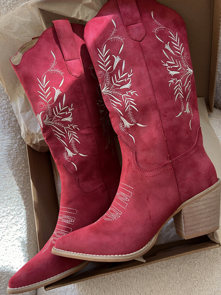 Red cowboy boots with white embroidery in a cardboard box.