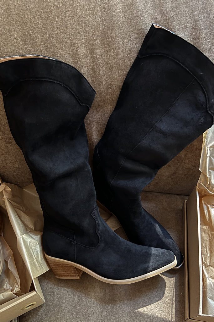 Black knee-high boots on a textured surface